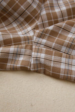 Close-up of brown and white plaid fabric on a beige surface