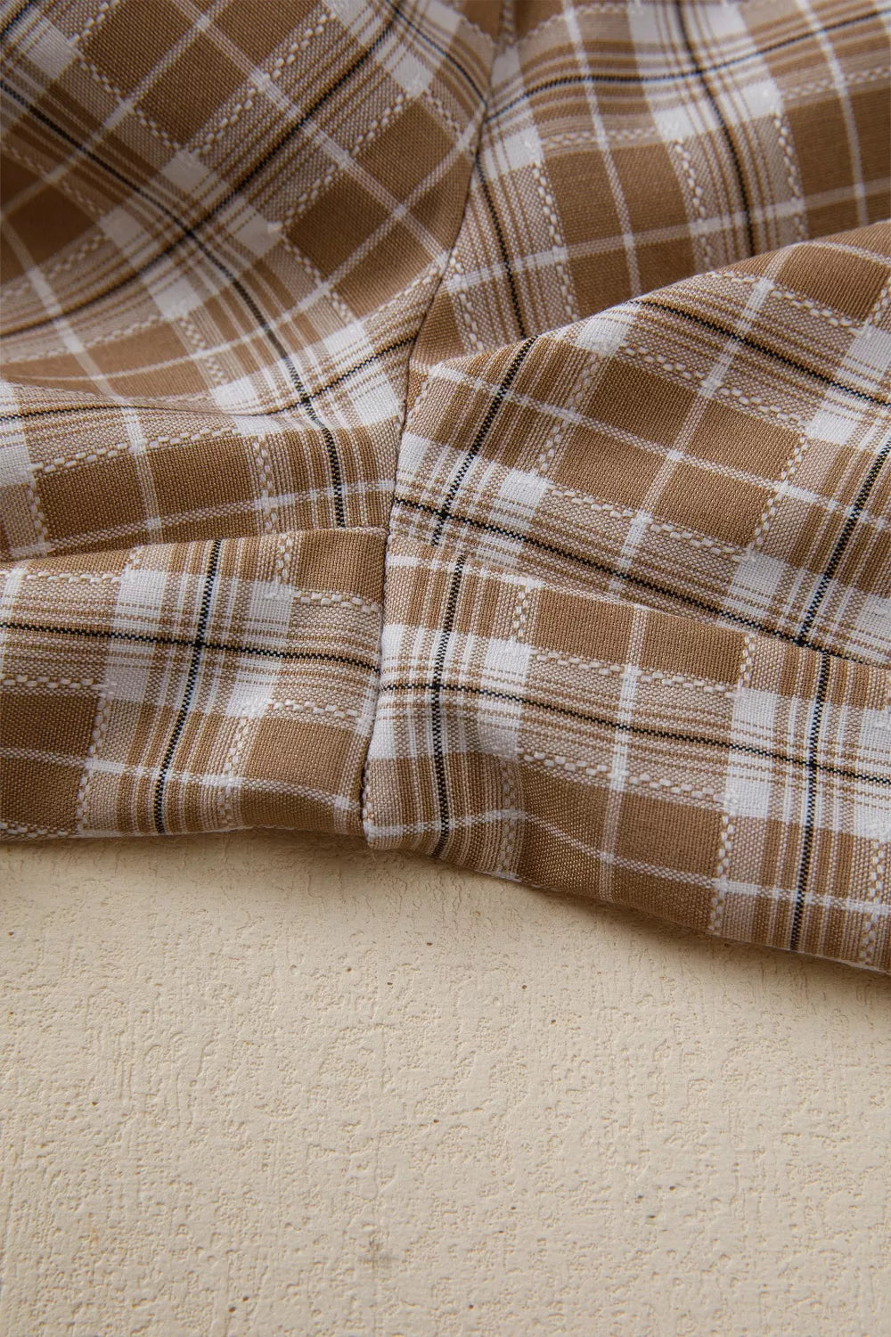 Close-up of brown and white plaid fabric on a beige surface