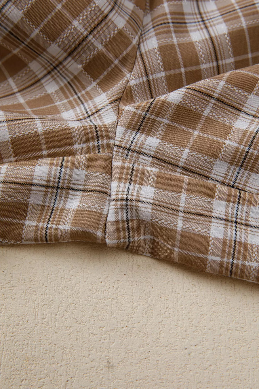Close-up of brown and white plaid fabric on a beige surface