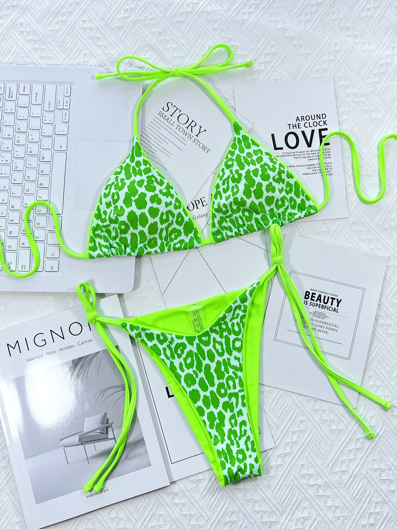 Green leopard print bikini set on a textured surface with magazines underneath