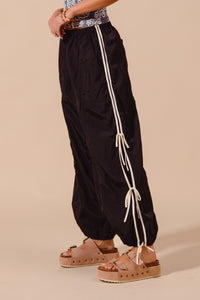 Black pants with white drawstrings worn by a person on a beige background