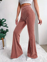 Person wearing ribbed brown flared pants with a white background