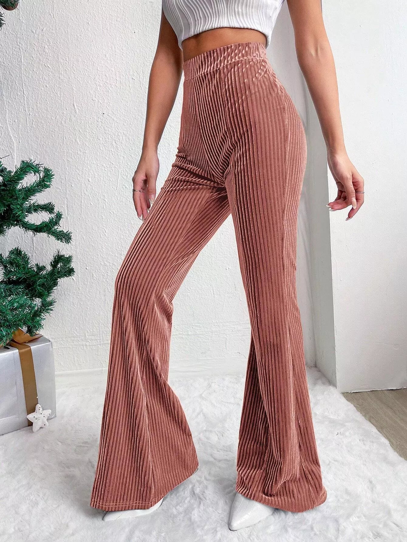 Person wearing ribbed brown flared pants with a white background
