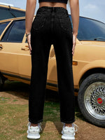 Person wearing black jeans standing in front of a vintage car.
