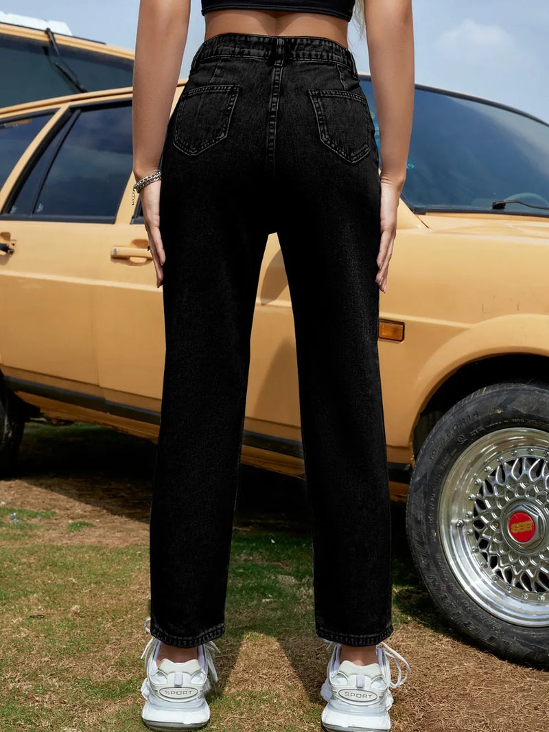 Person wearing black jeans standing in front of a vintage car.