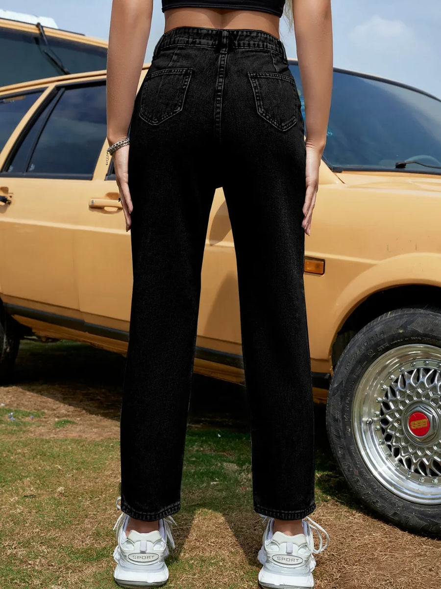 Person wearing black jeans standing in front of a vintage car.