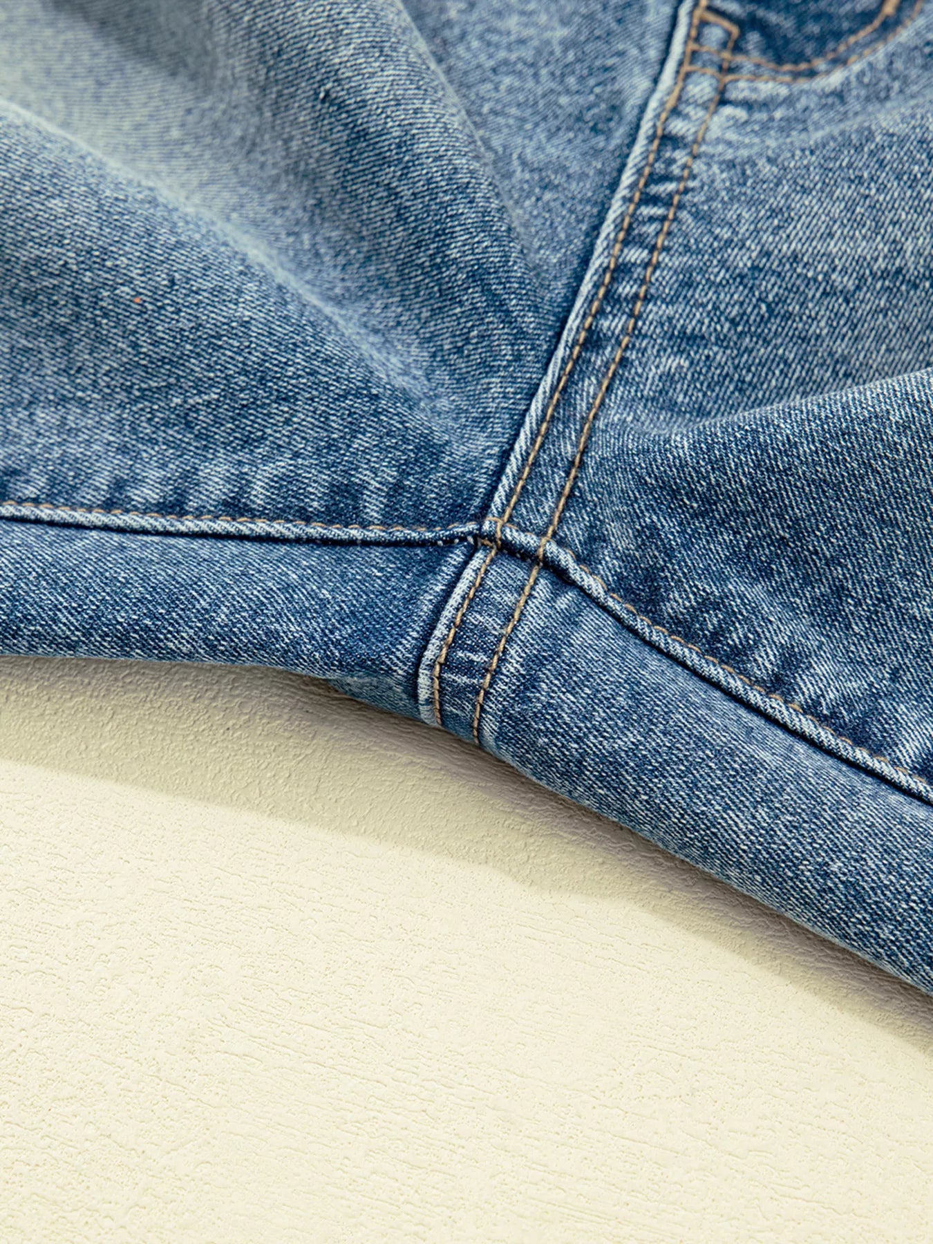 Close-up of blue denim fabric on a beige surface