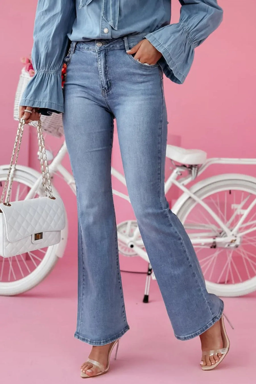 Person wearing blue jeans and a denim shirt with a white bicycle in the background.