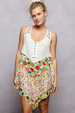 Woman wearing a white top with colorful floral skirt against a gray background