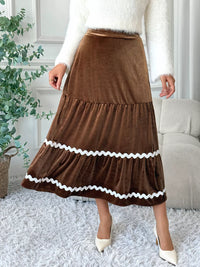 Person wearing a brown skirt with white trim in a home setting