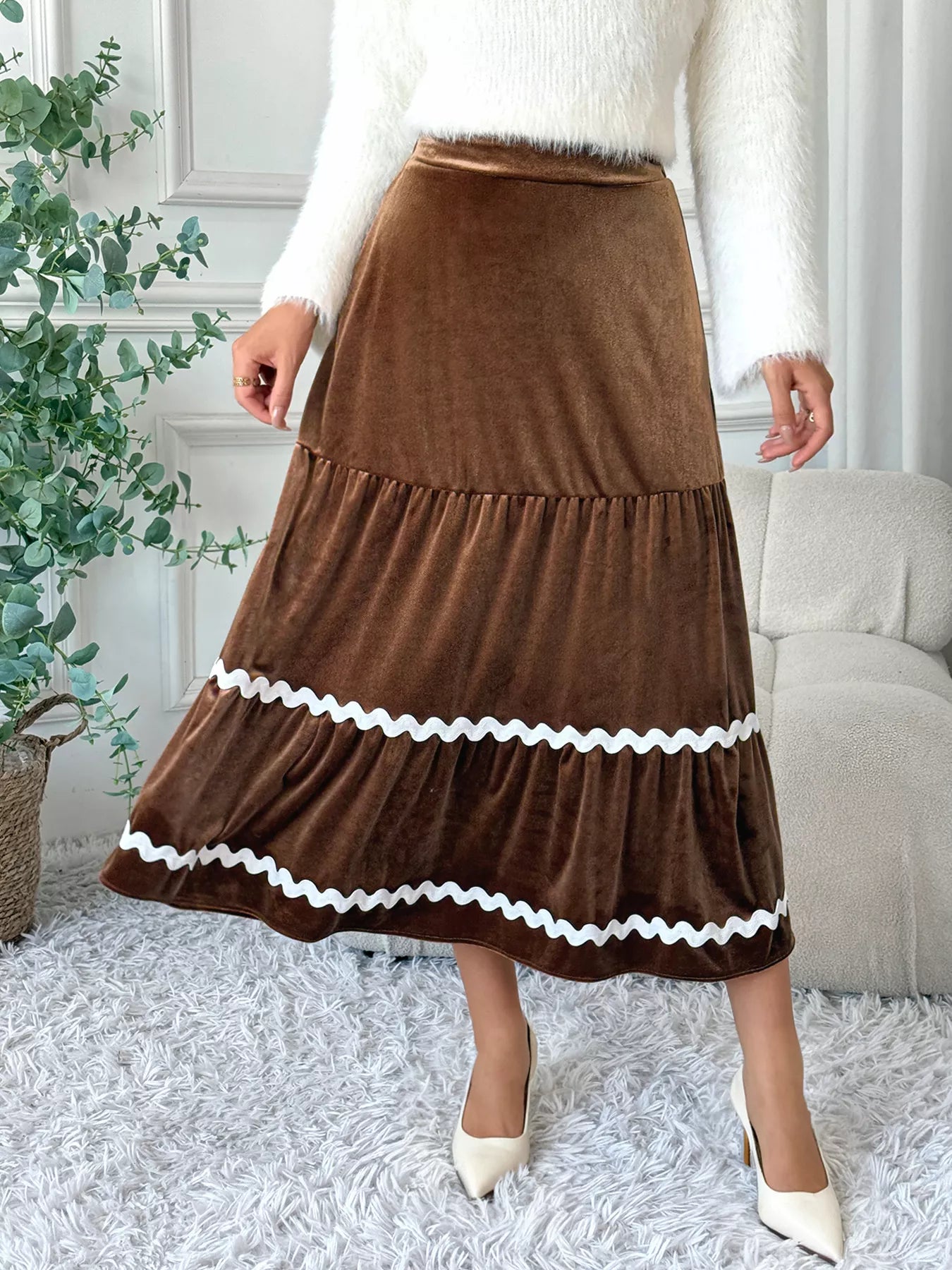 Person wearing a brown skirt with white trim in a home setting