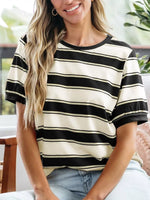 Woman wearing a black and white striped shirt sitting indoors.