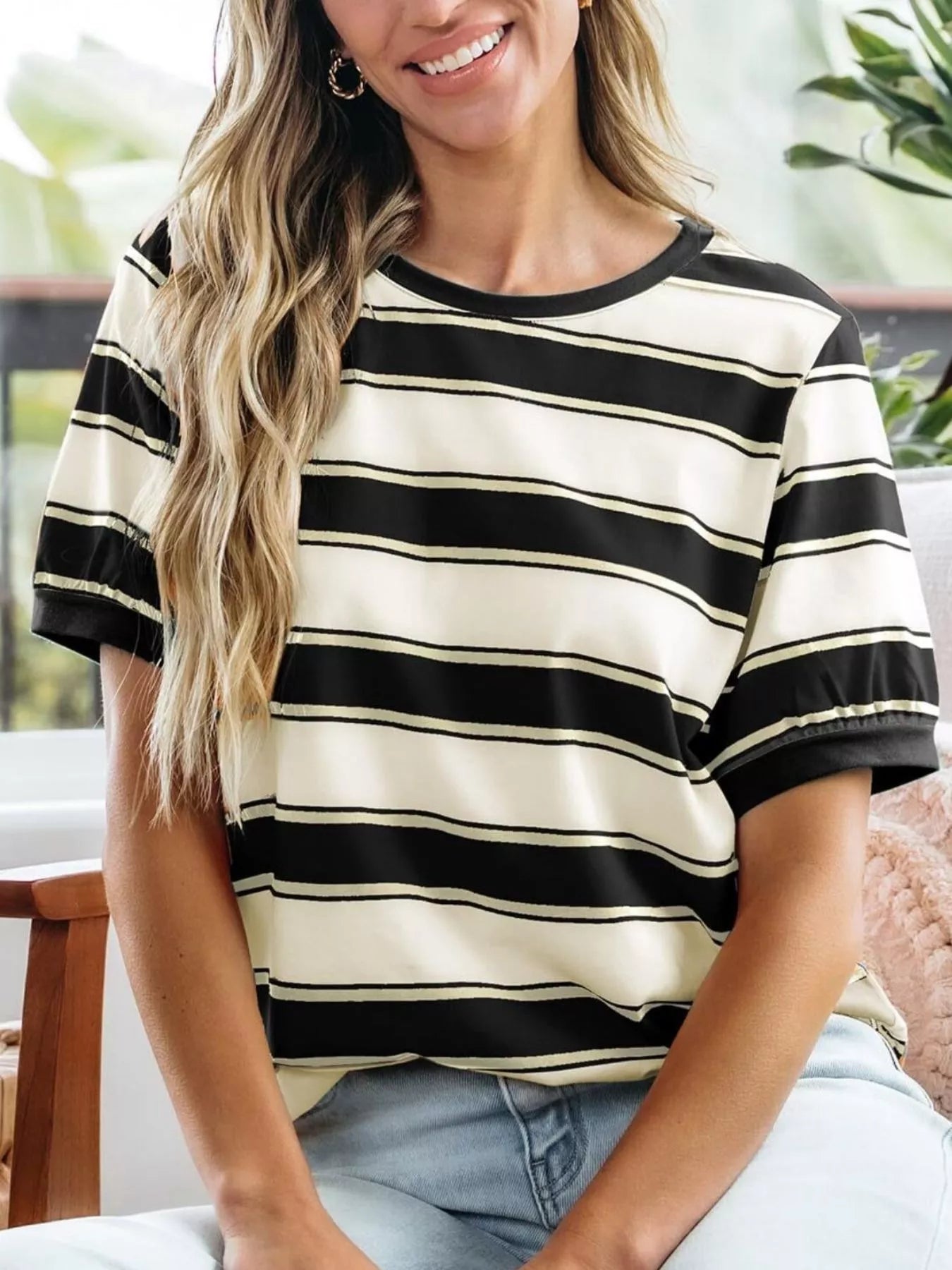 Woman wearing a black and white striped shirt sitting indoors.