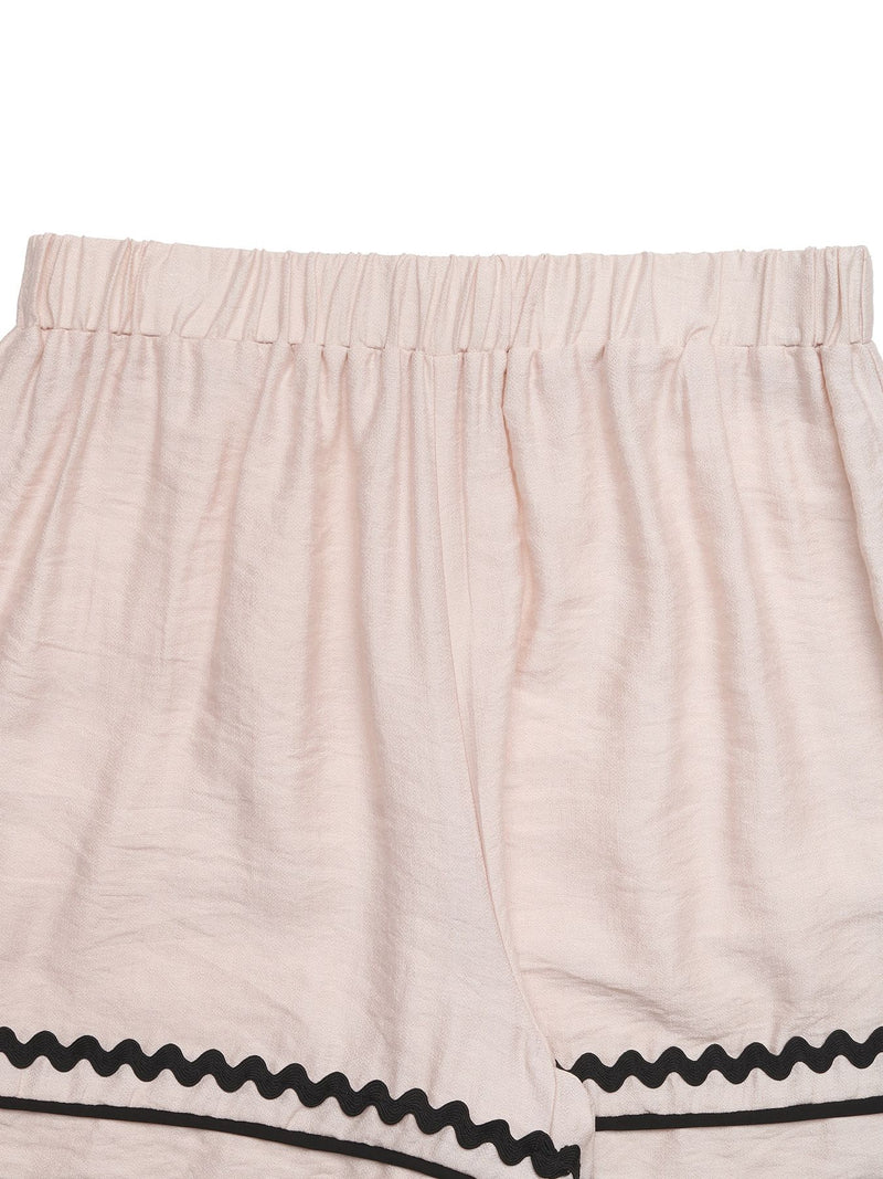 Beige shorts with black trim on a white background