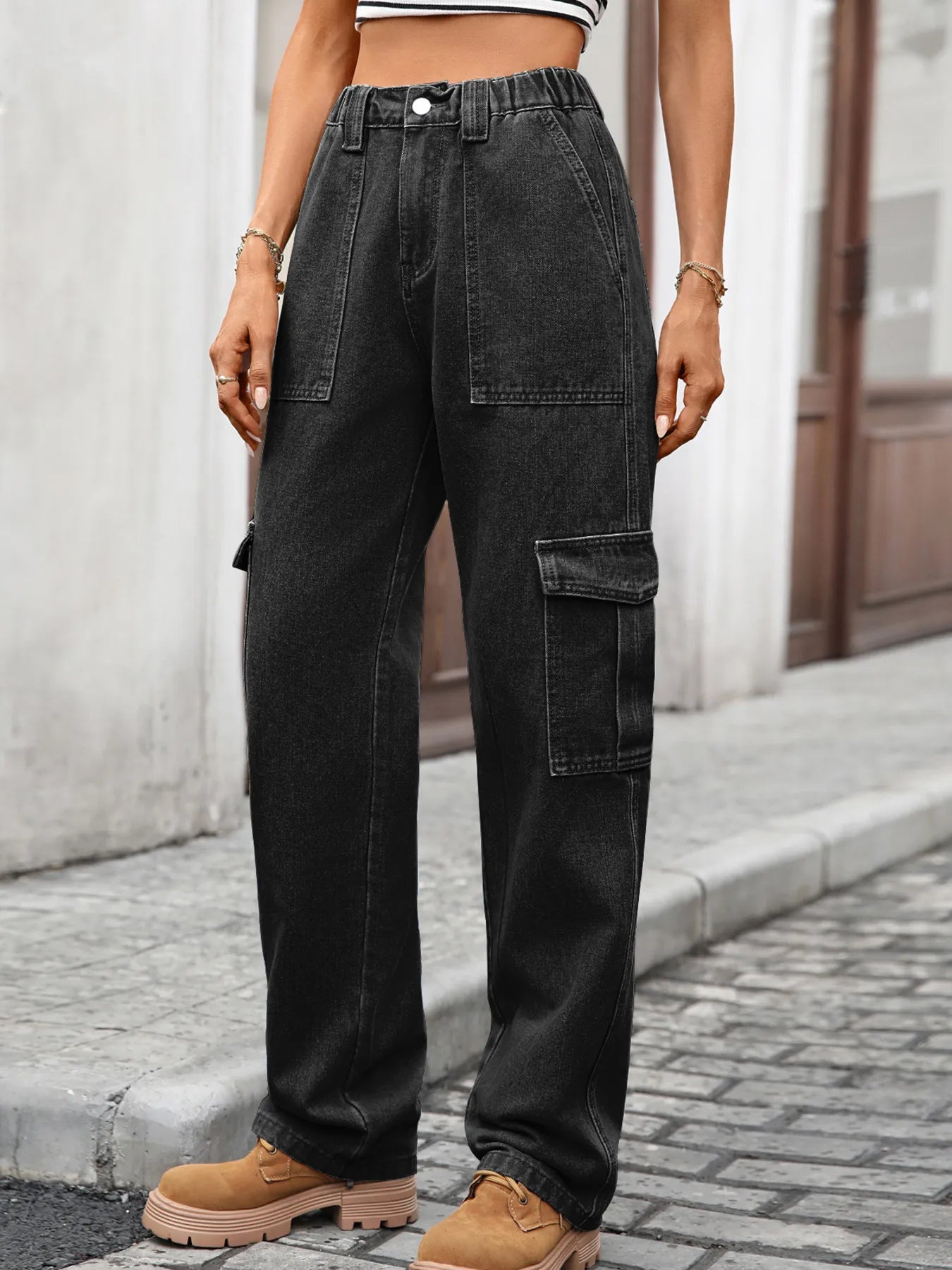 Person wearing black cargo pants and tan boots on a street.
