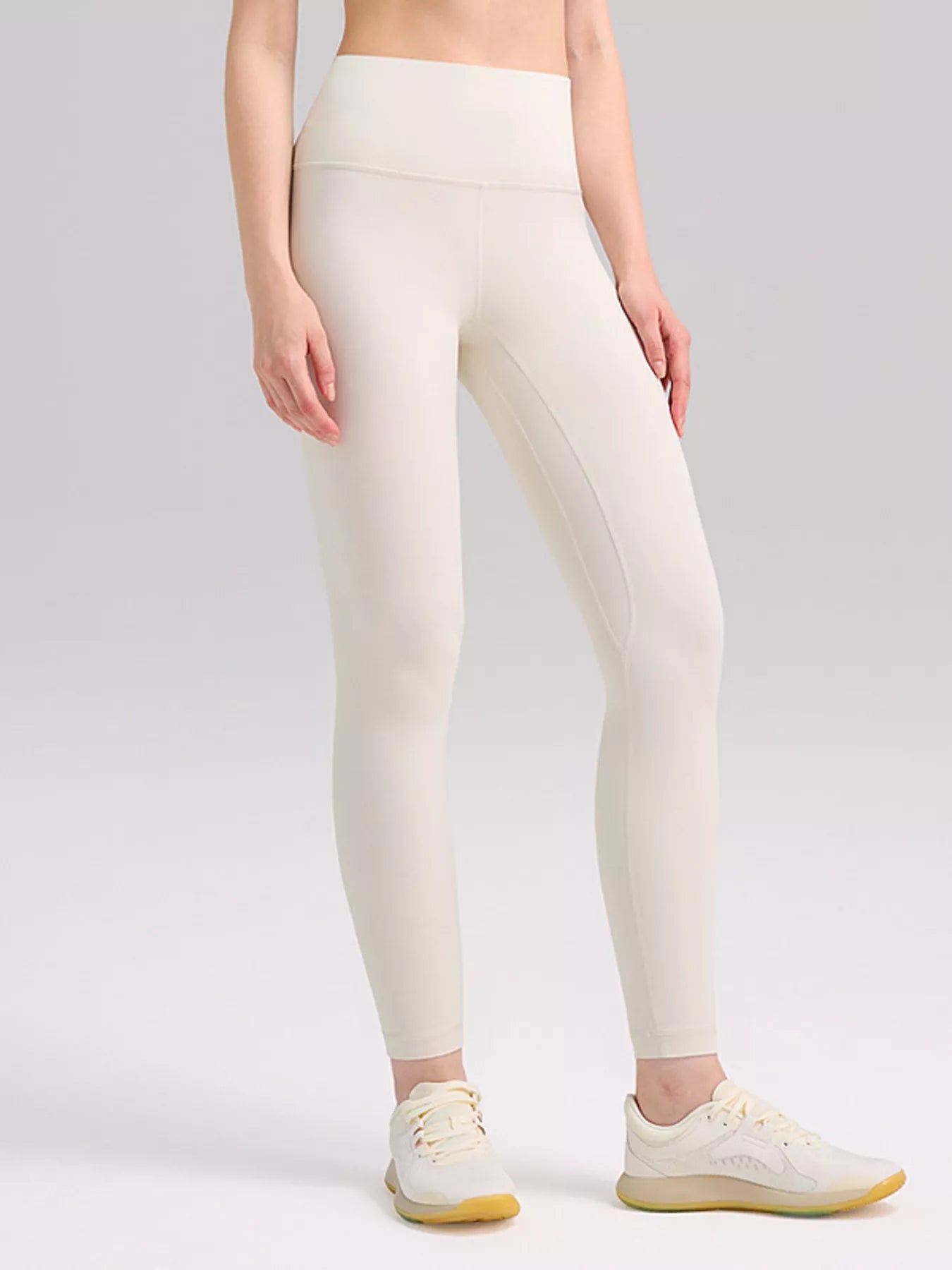 Person wearing white leggings on a plain background