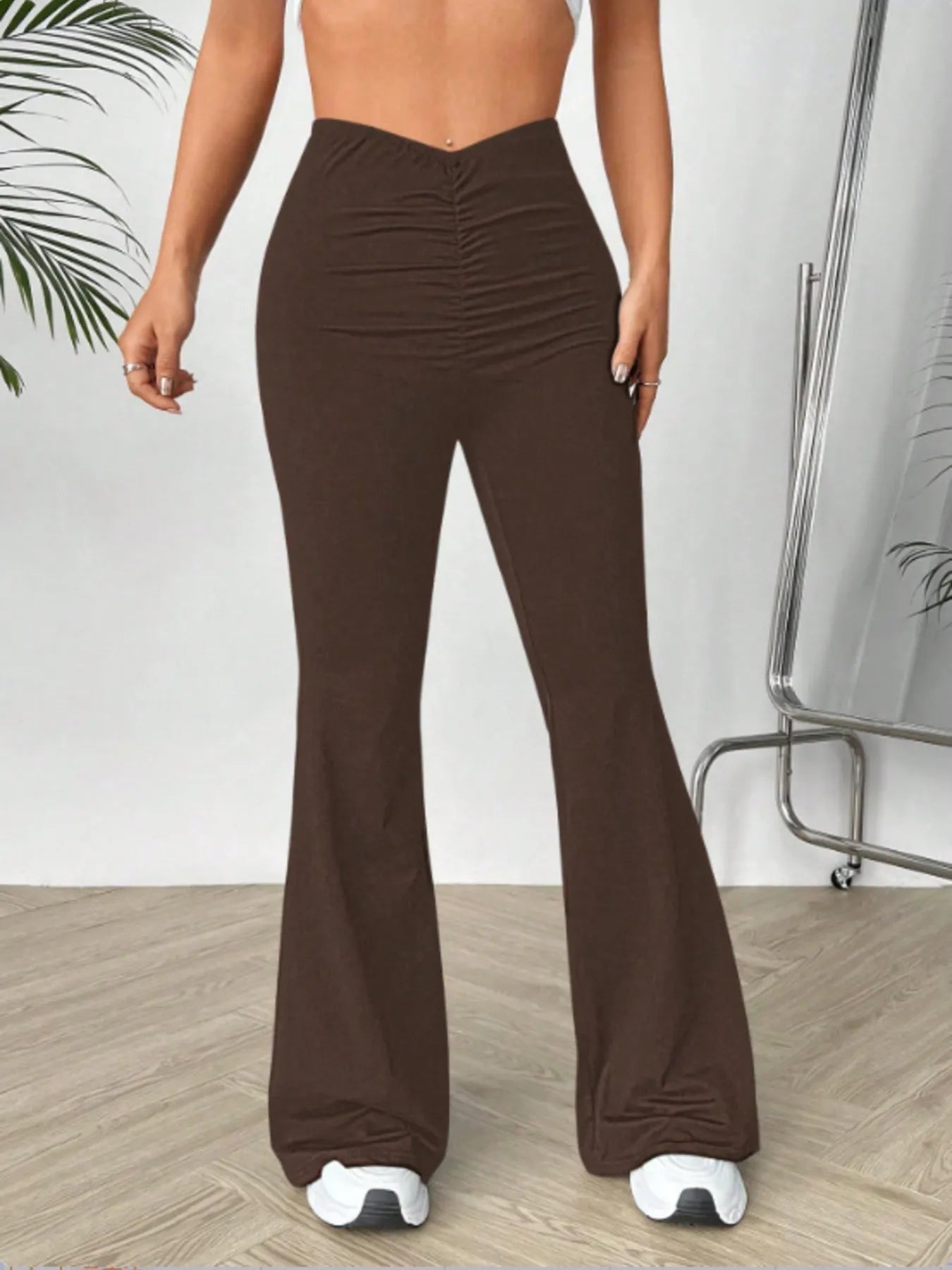 Brown flared pants worn by a person on a light wooden floor.