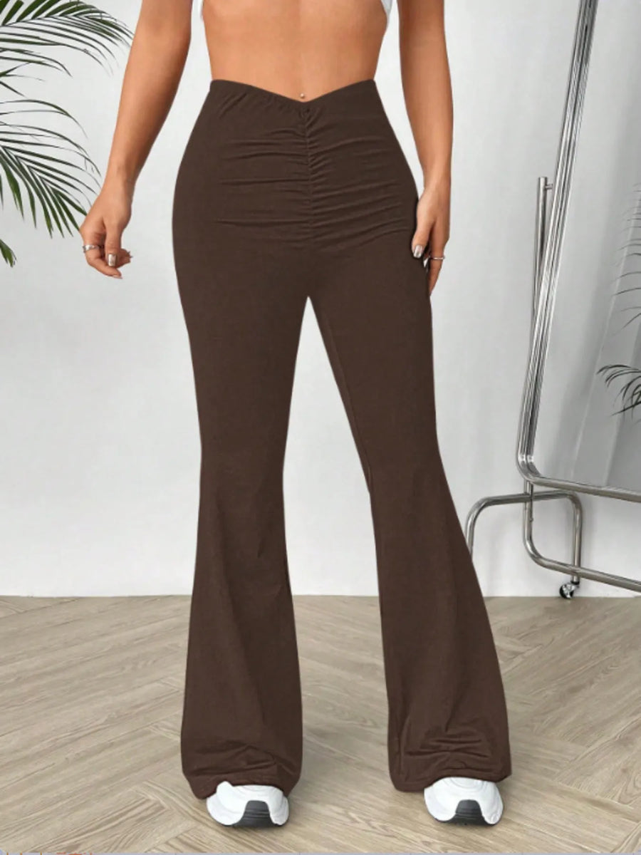 Brown flared pants worn by a person on a light wooden floor.