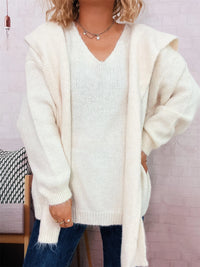 Person wearing a cream cardigan over a white shirt with a blurred background