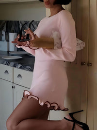 Person wearing a pink dress with ruffled hem in a kitchen setting