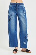 Blue distressed jeans with star patches on a white background