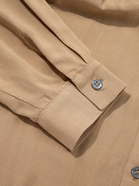 Close-up of a beige shirt with rolled-up sleeve and button detail