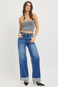 Woman wearing a strapless top and blue jeans on a white background
