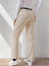 Person wearing beige pants and white sneakers in a minimalistic setting