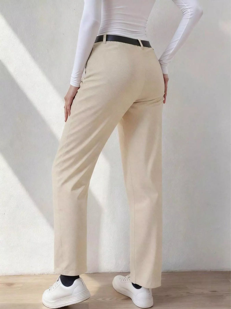 Person wearing beige pants and white sneakers in a minimalistic setting