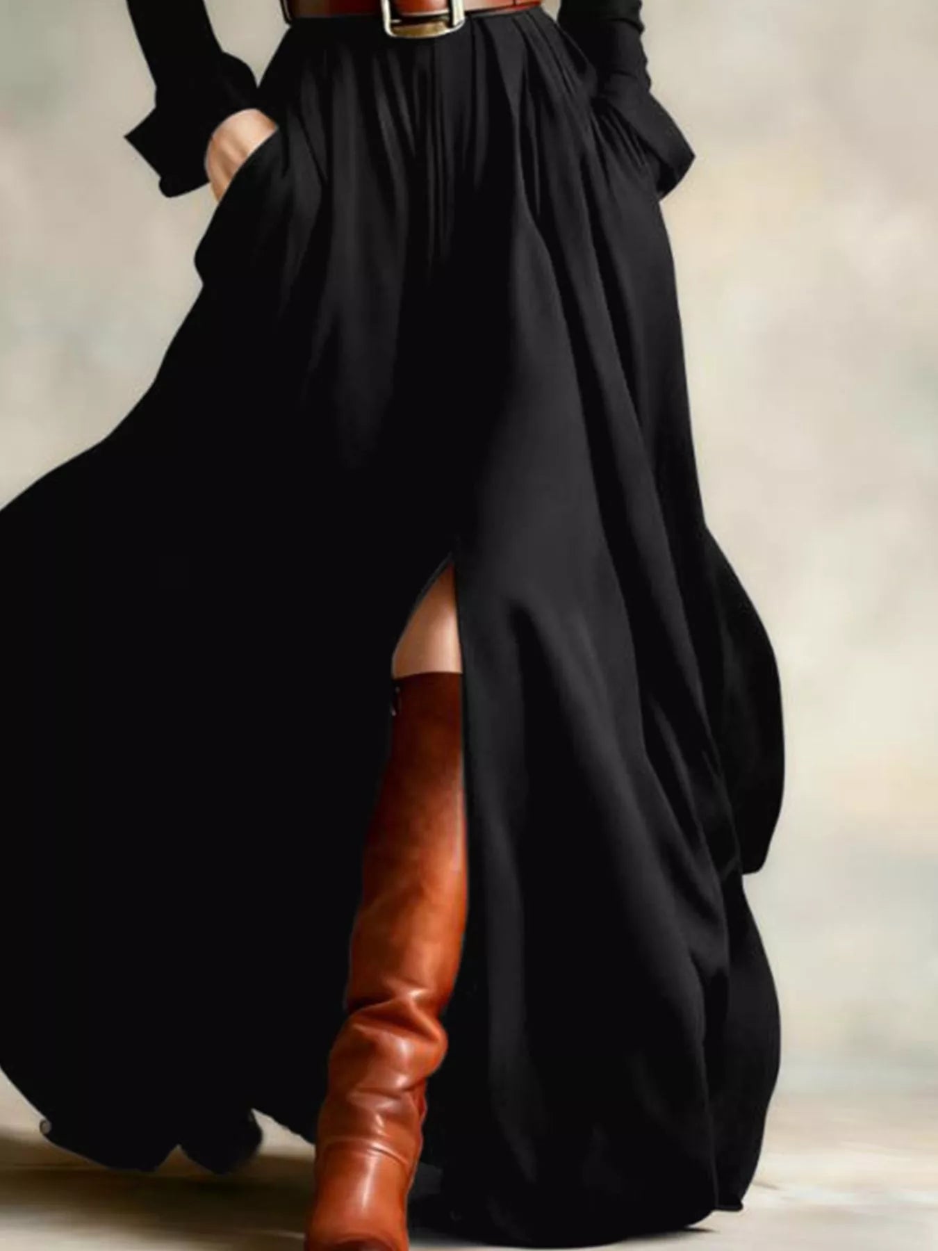 Person wearing a long black dress with a belt and brown knee-high boots on a neutral background