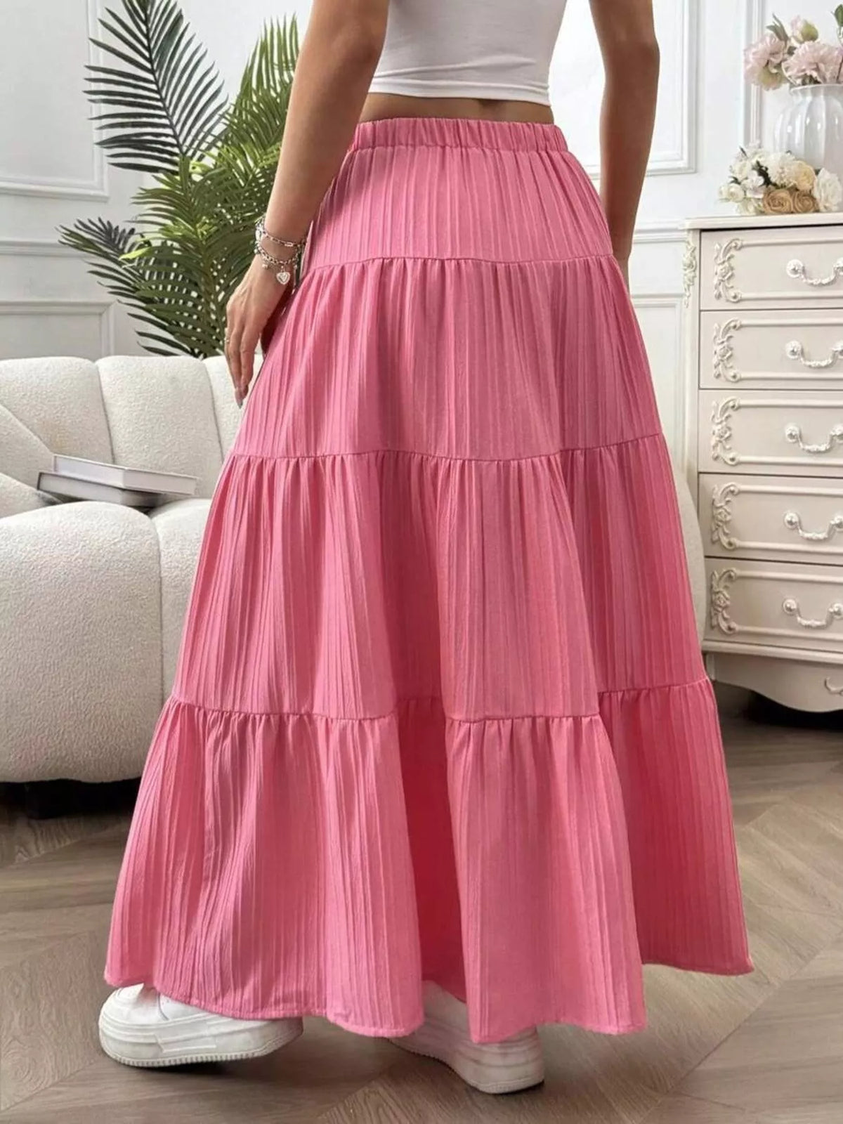 Person wearing a pink tiered skirt in a room with a couch and dresser.