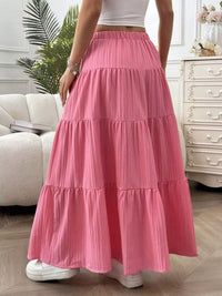 Person wearing a pink tiered skirt in a room with a couch and dresser.