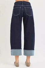 Navy blue wide-leg jeans with cuffed hems on a white background