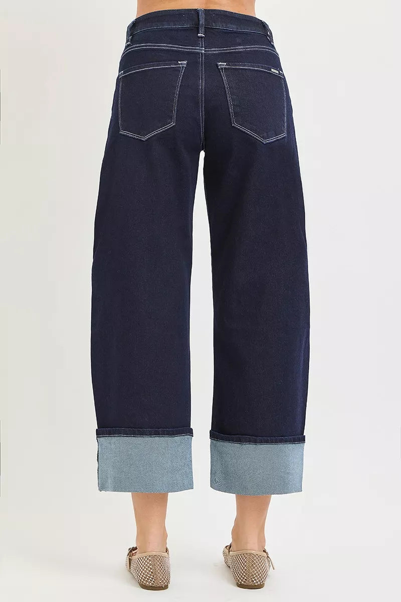 Navy blue wide-leg jeans with cuffed hems on a white background
