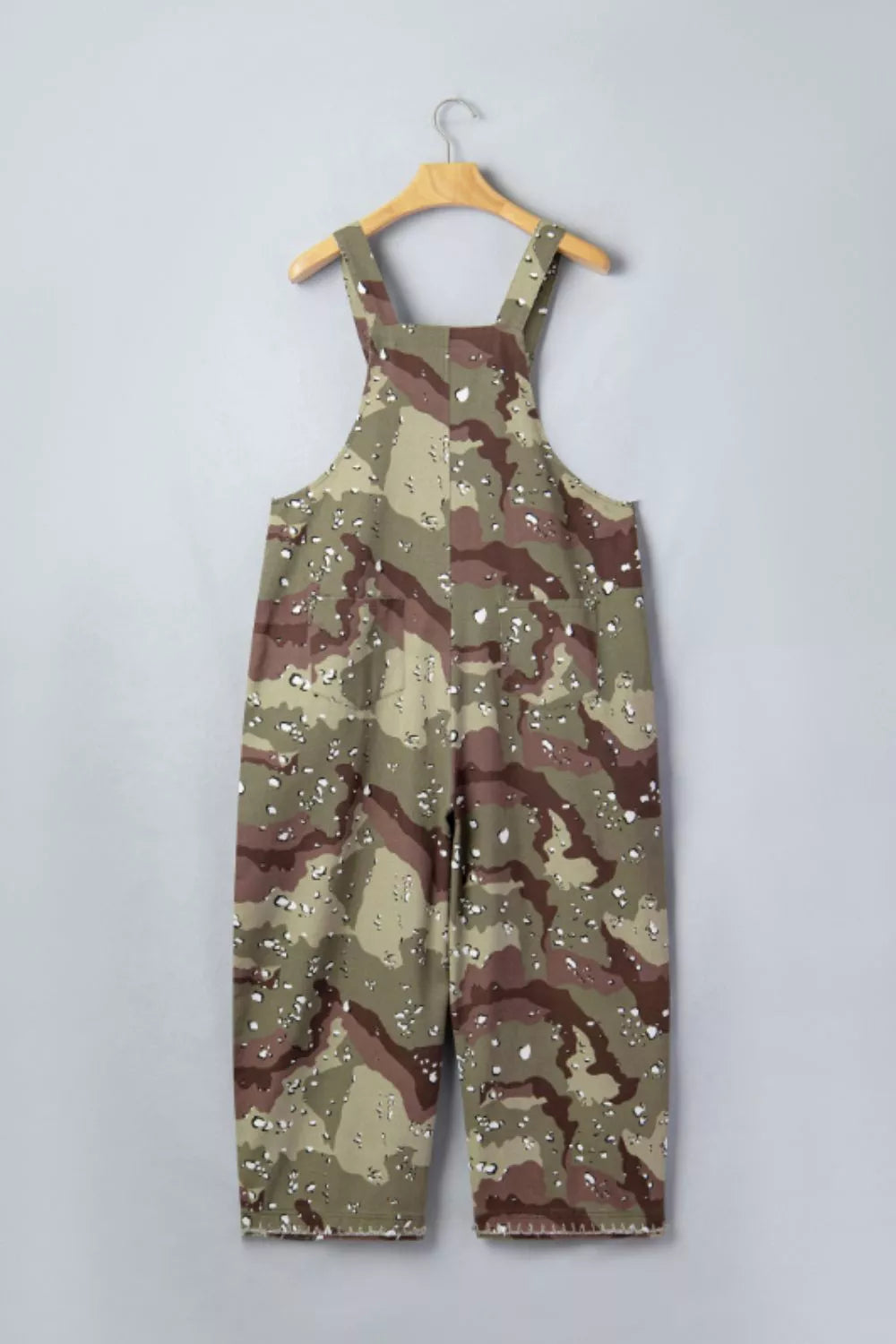 Camouflage overalls on a hanger against a light gray background