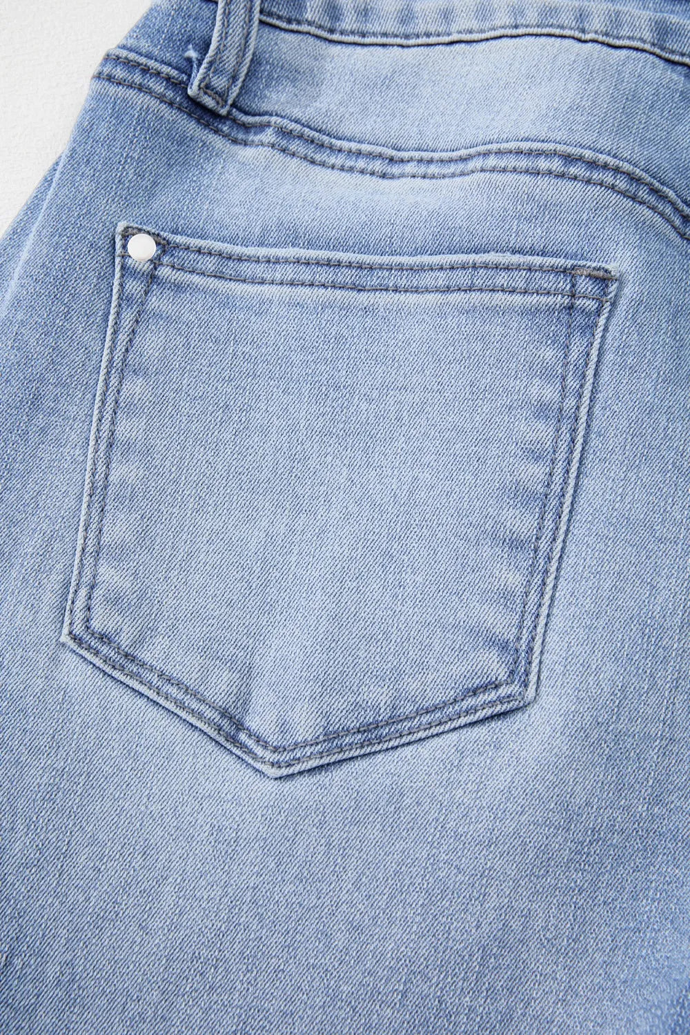 Close-up of a blue denim pocket with a button.