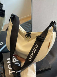 Beige shoulder bag with black strap featuring 'SUICHIAO' branding on a reflective surface.