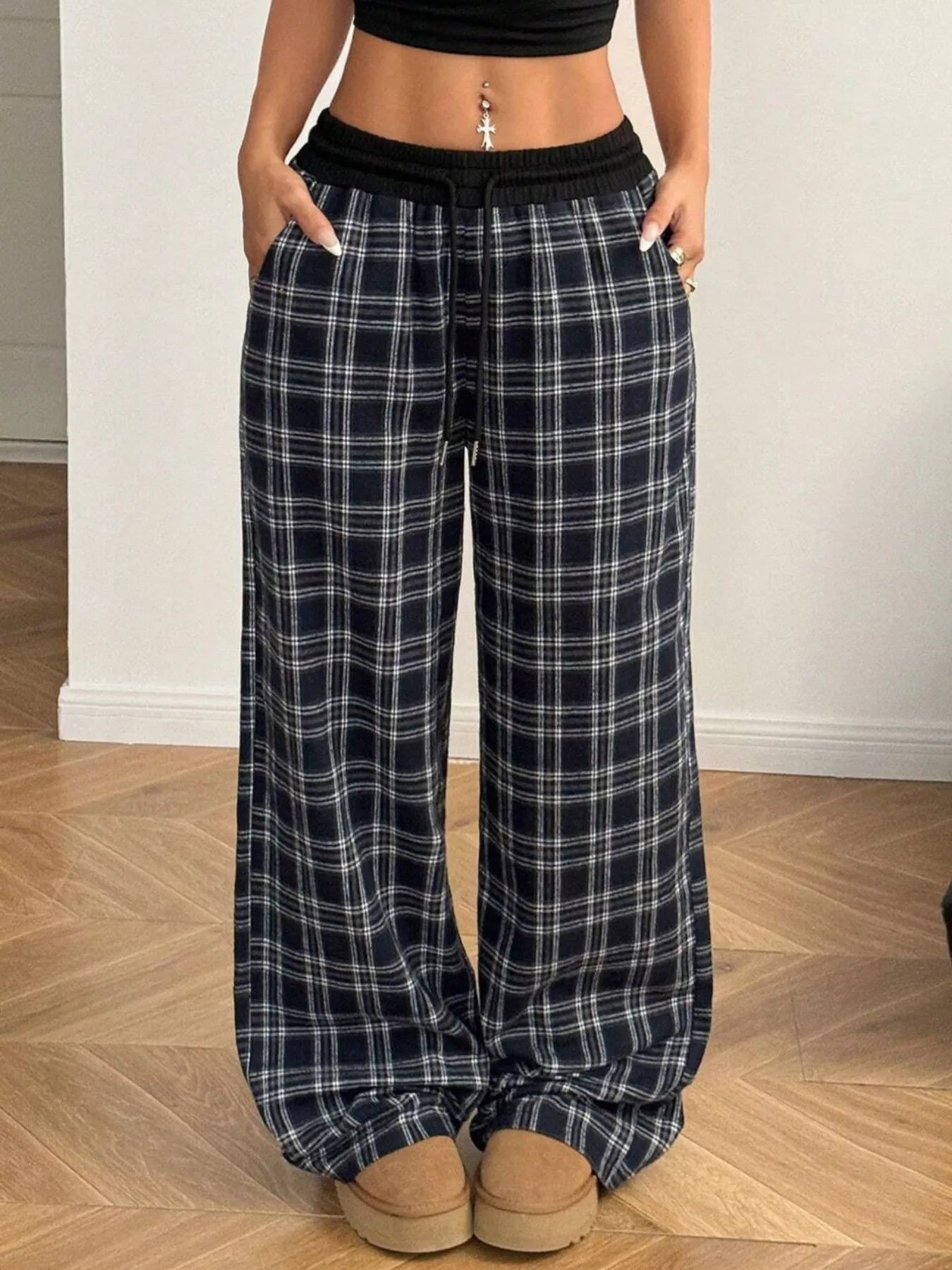 Person wearing black and white plaid pajama pants on a wooden floor.
