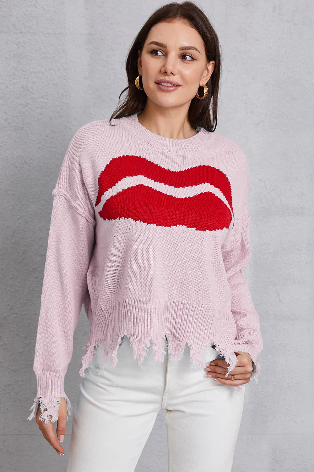Woman wearing a pink sweater with a red and white design on a gray background