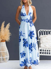 Woman wearing a blue floral dress against a gray wall with decorative elements.