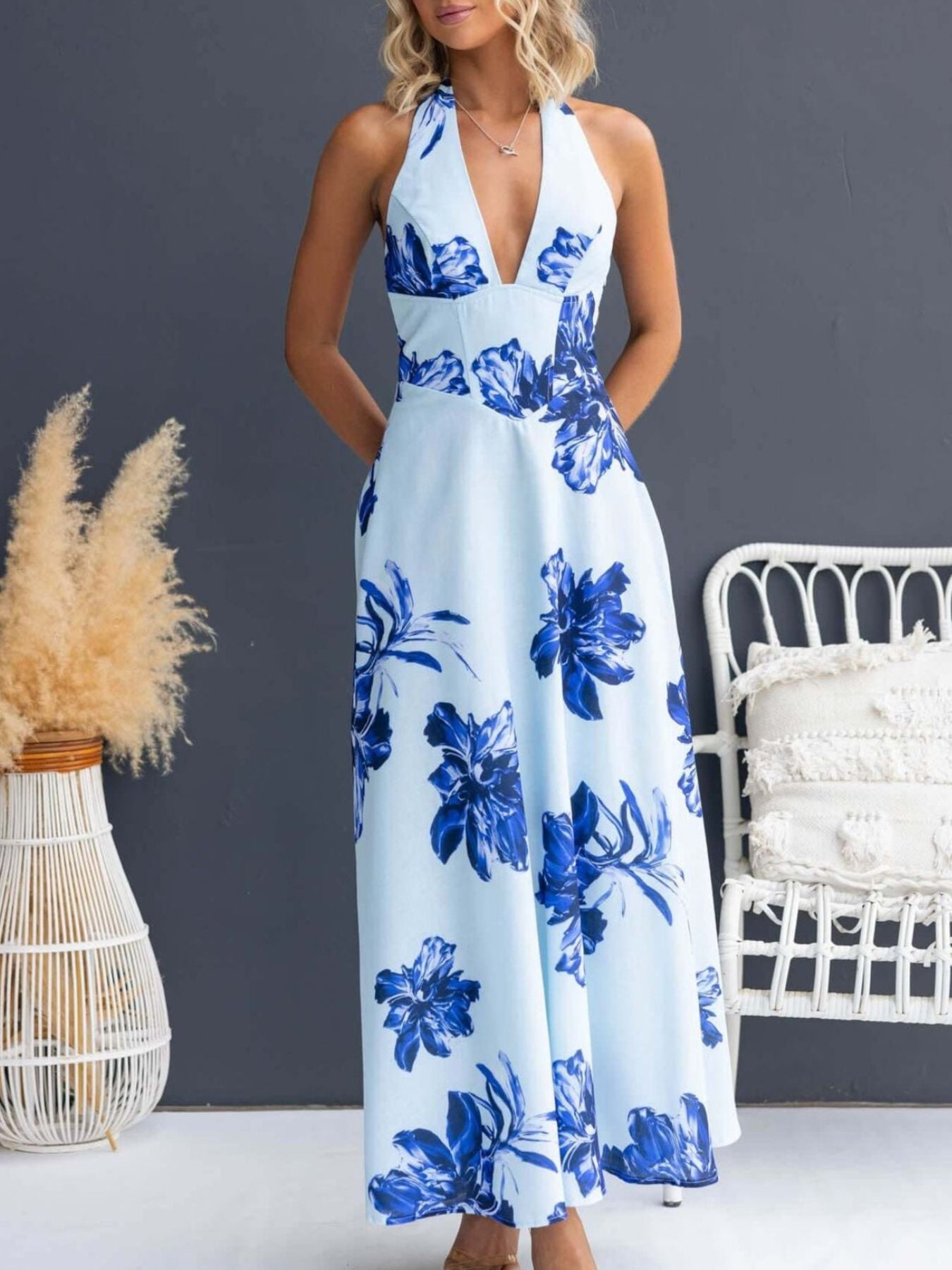 Woman wearing a blue floral dress against a gray wall with decorative elements.