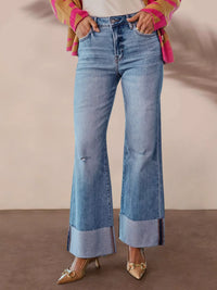 Person wearing blue flared jeans with a plain background
