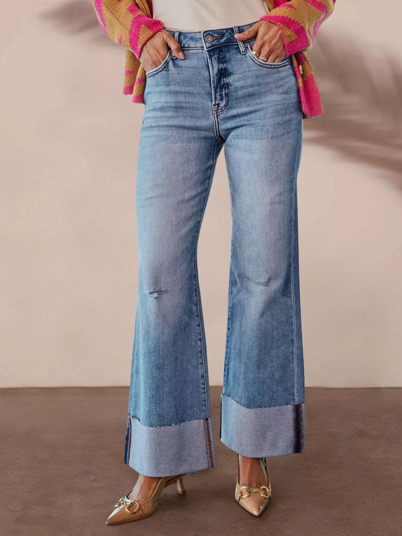 Person wearing blue flared jeans with a plain background