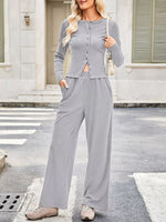 Woman wearing a gray outfit with a matching cardigan and pants on a city street.