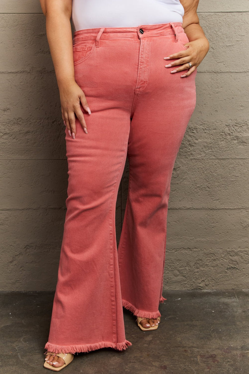 Person wearing pink flared jeans against a gray wall.