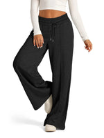Person wearing black wide-leg pants with a white top on a white background