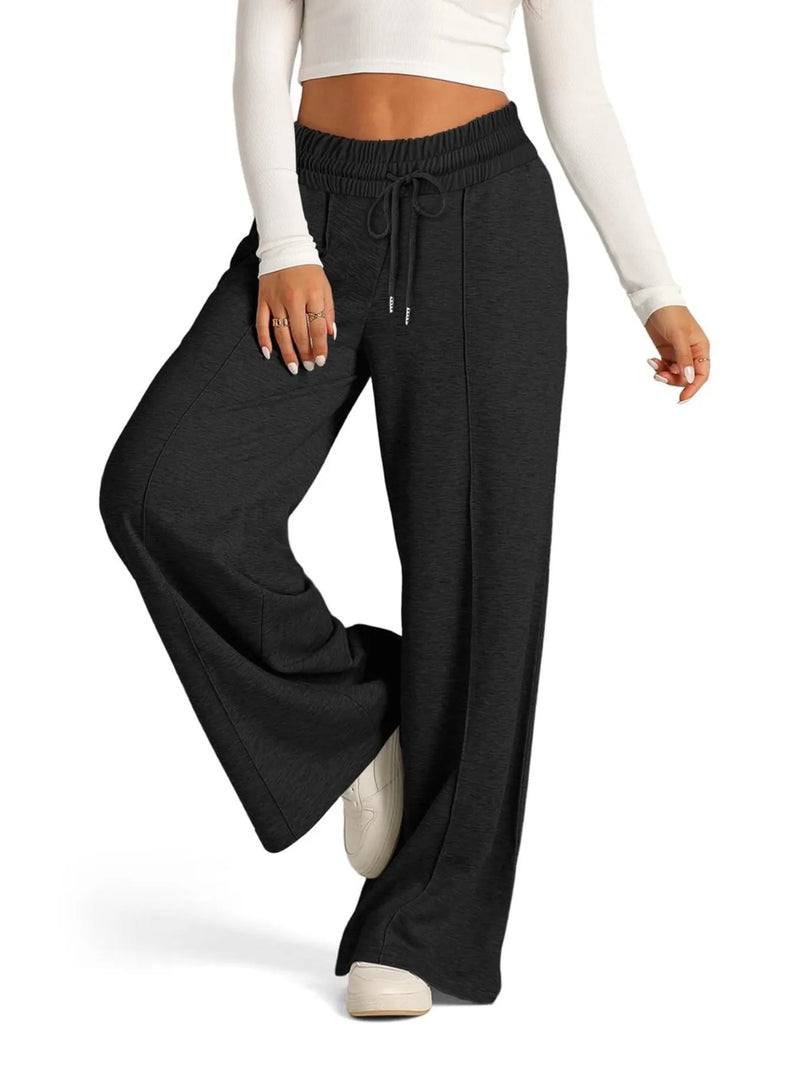 Person wearing black wide-leg pants with a white top on a white background