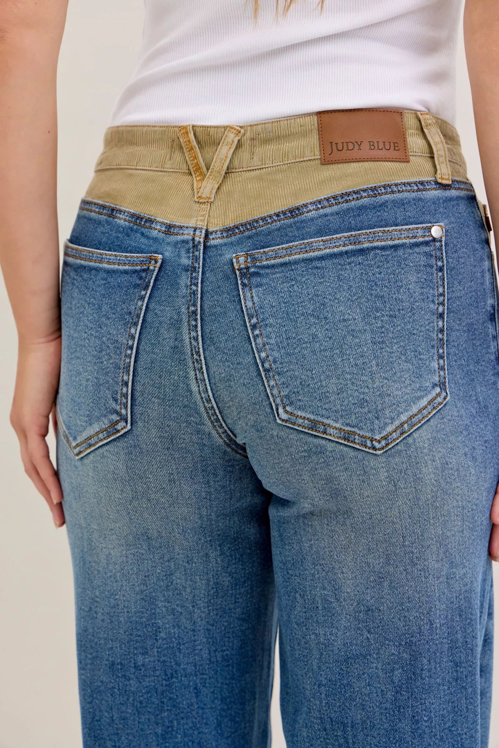Blue jeans with a beige belt and visible brand label on a neutral background