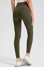 Person wearing olive green leggings and white sneakers on a white background