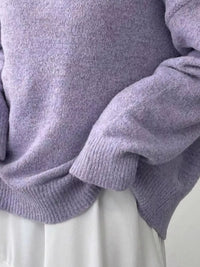 Close-up of a person wearing a light purple sweater with a neutral background